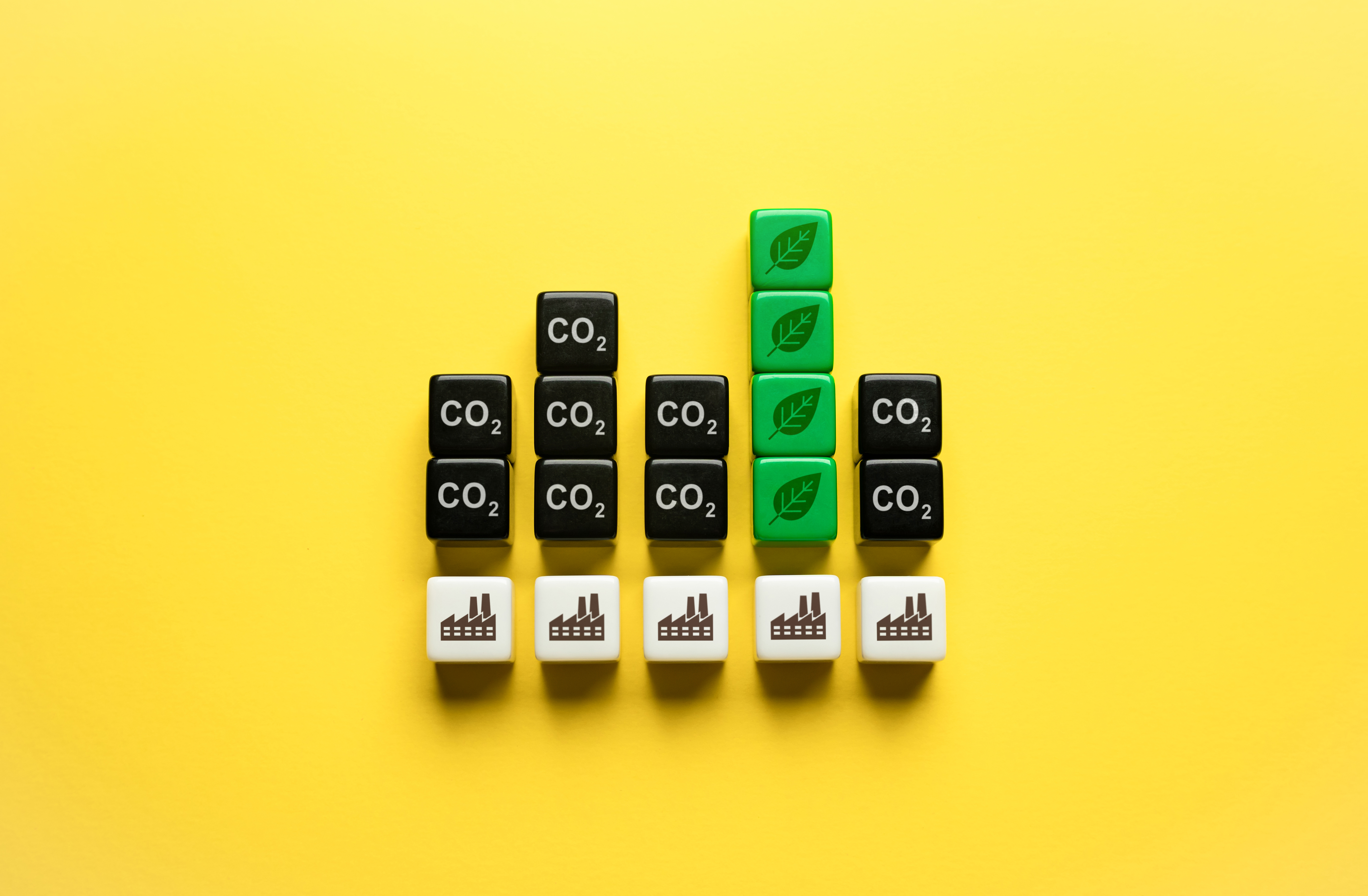 A bar chart made of blocks labeled CO2, with green leaf blocks showing reduced emissions