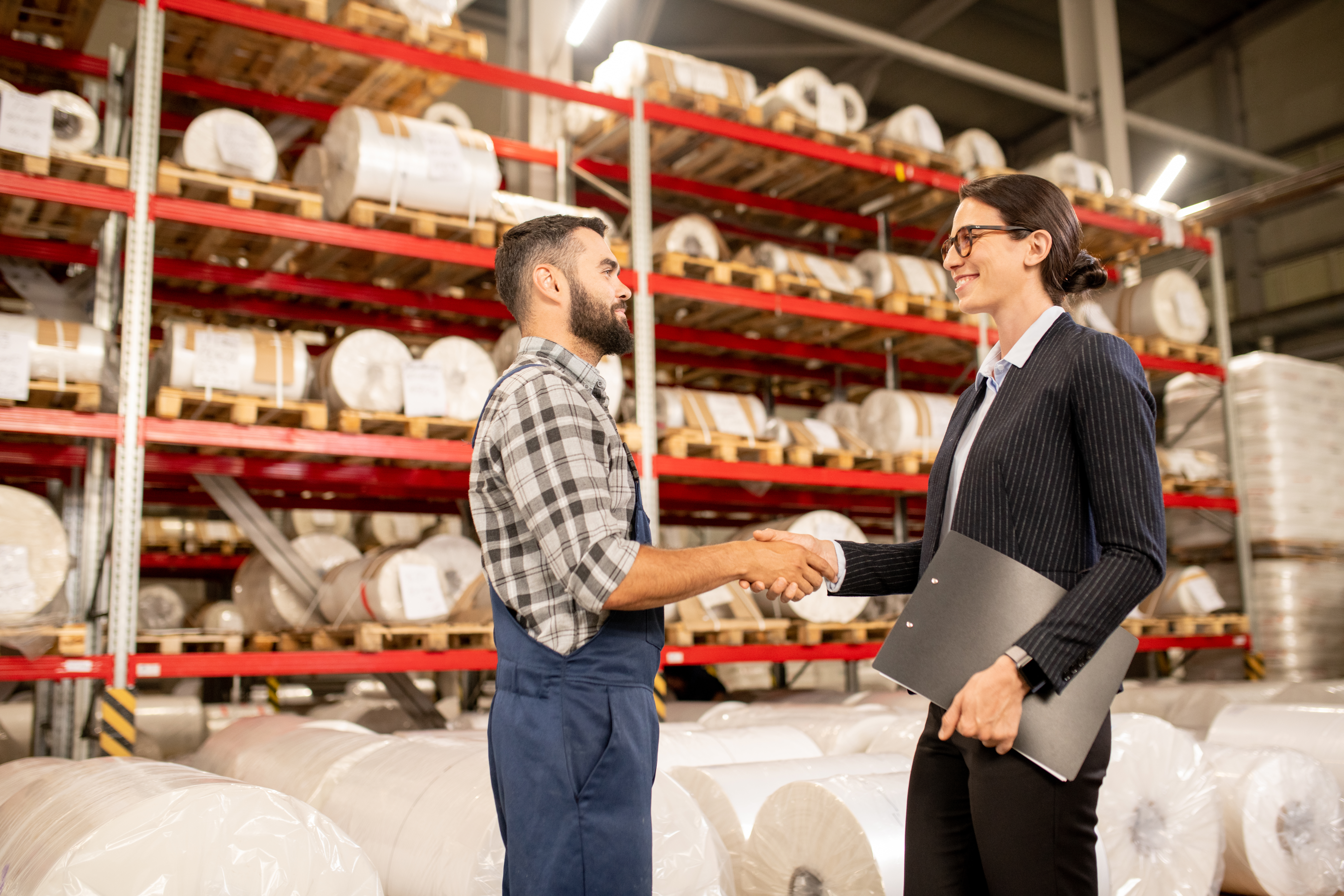 Two business partners shaking hands in a warehouse after a negotiation