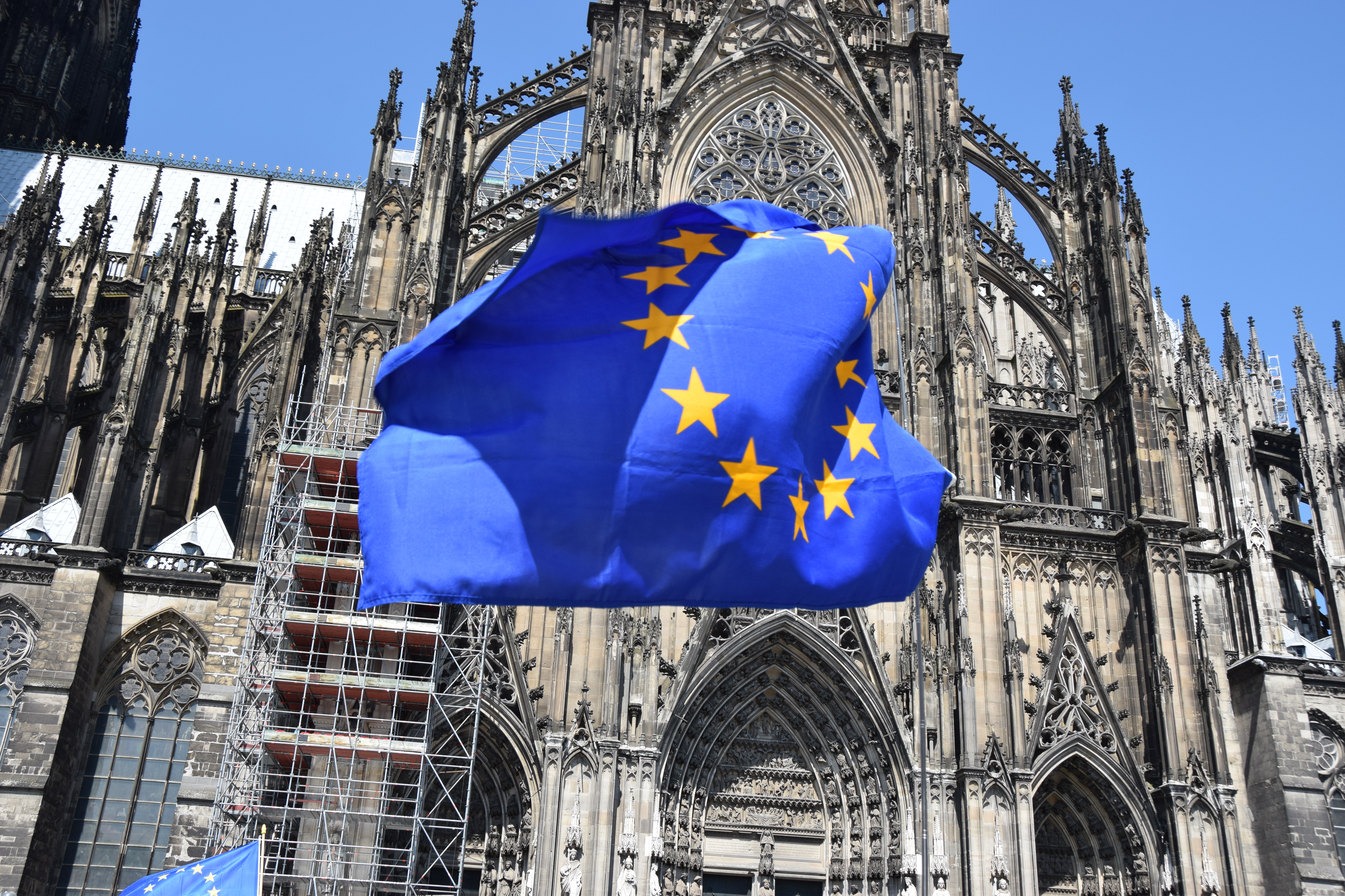 The European Union flag waving in front of a gothic cathedral