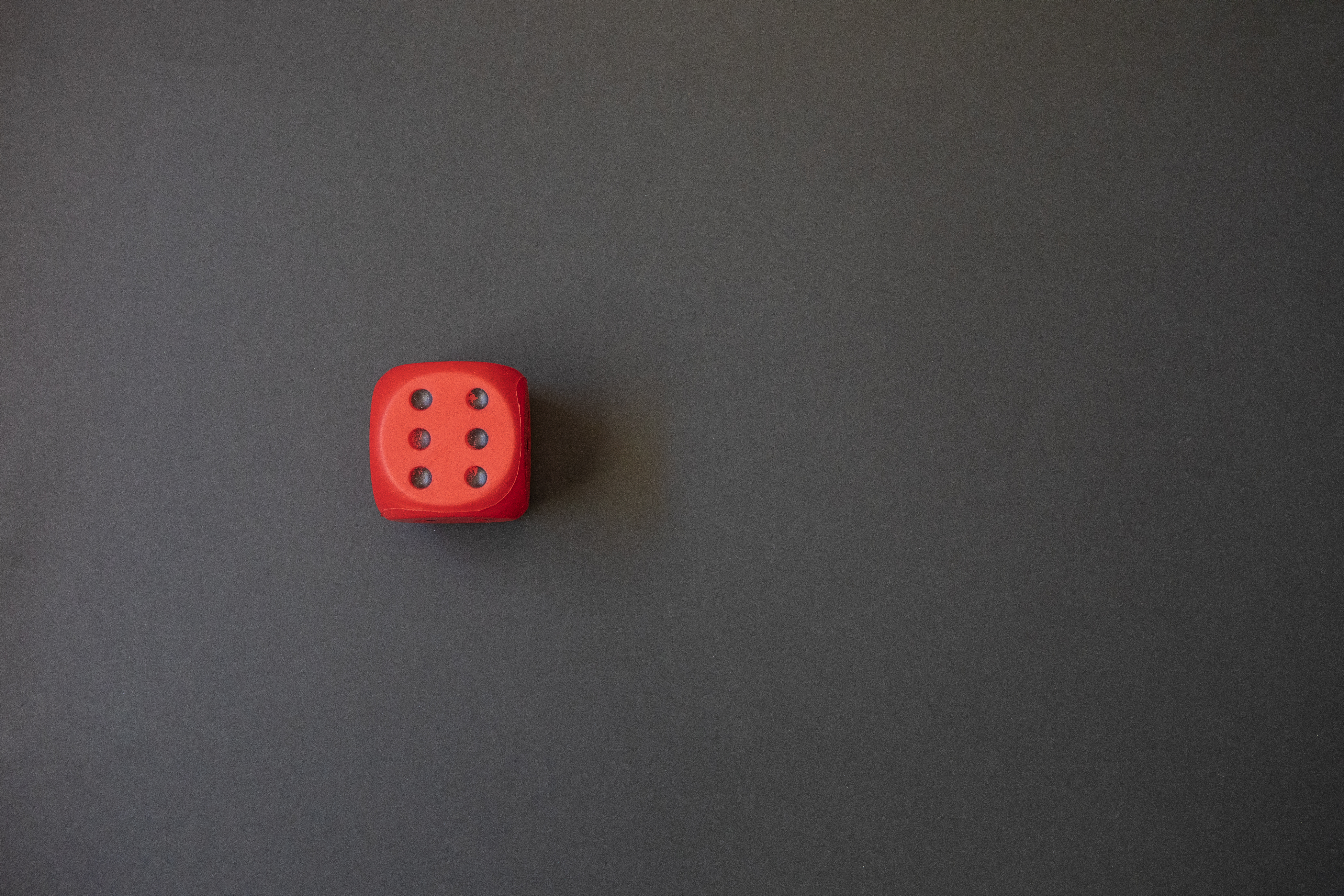 A single red die on a grey background