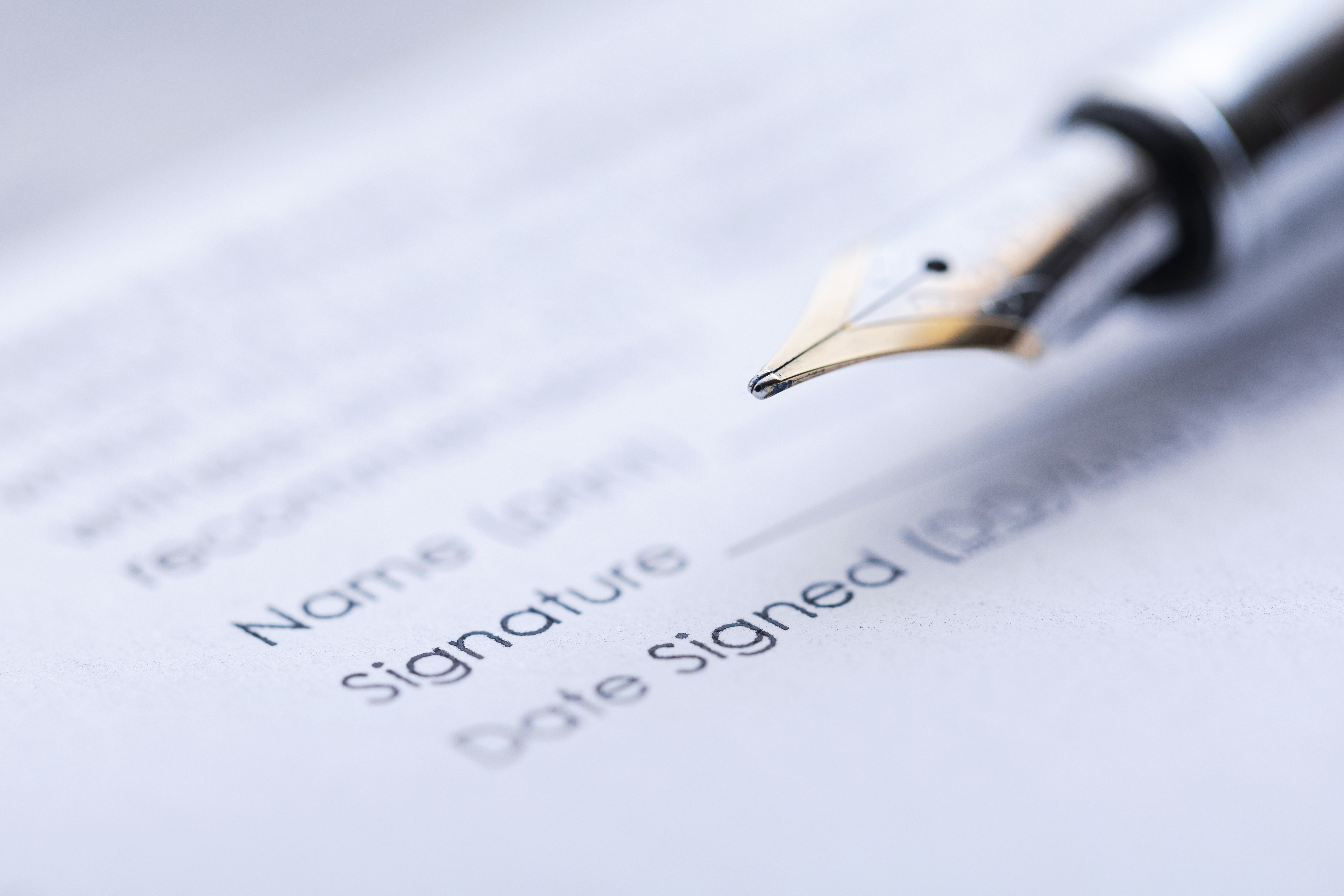 A fountain pen signing a business contract next to a signature line