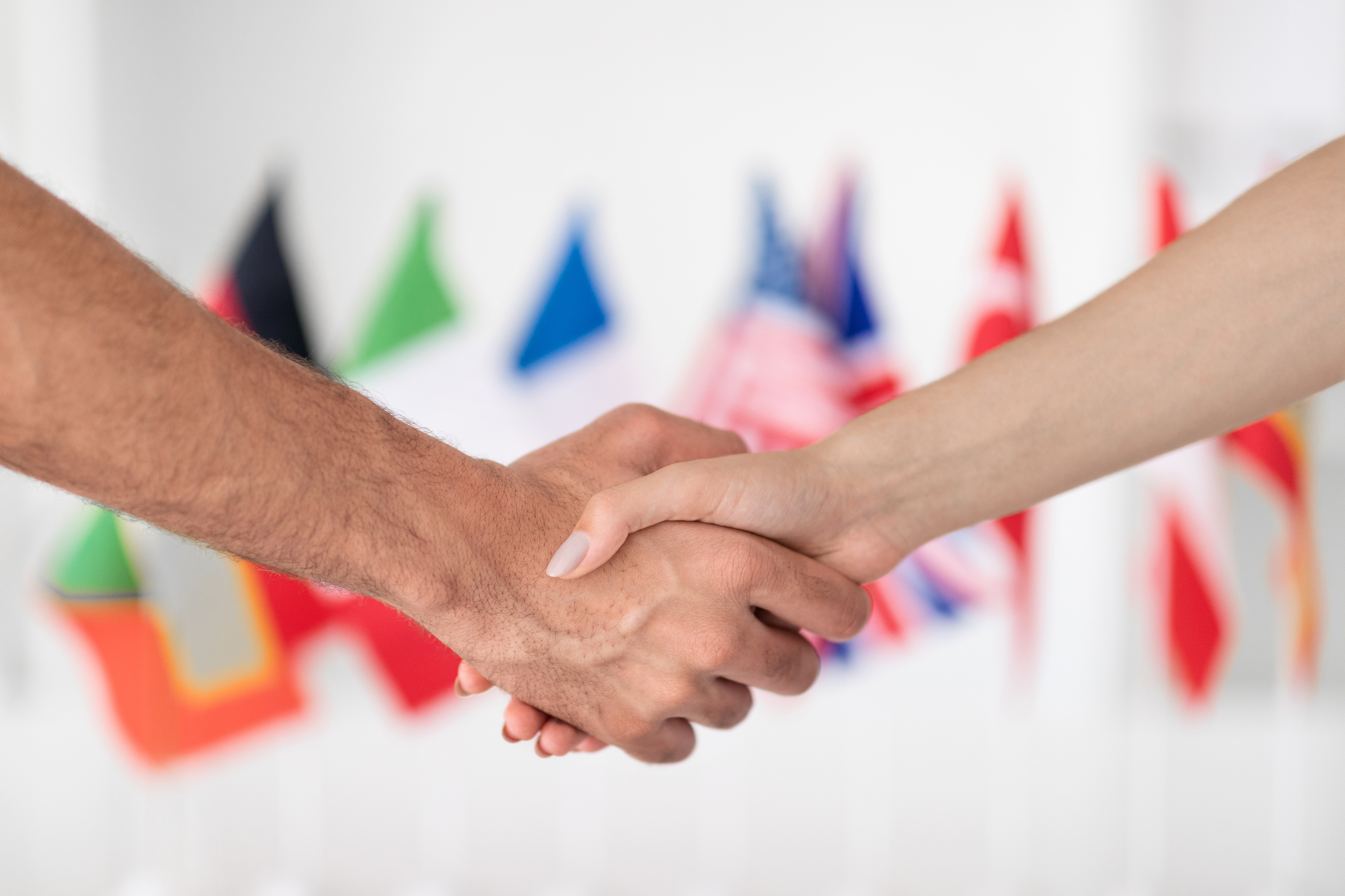 A business handshake with international flags in the background